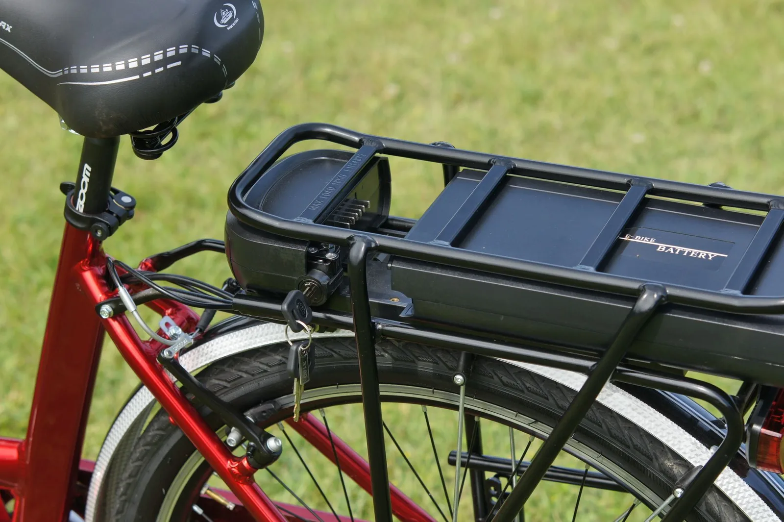 Close-up van een zwarte e-bike-accu op de bagagedrager van een rode elektrische fiets