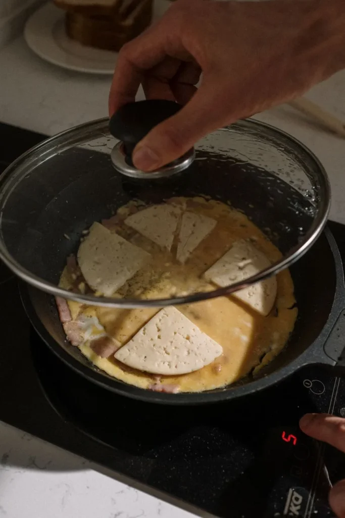 Hand die een glazen deksel op een koekenpan op een inductiekookplaat legt