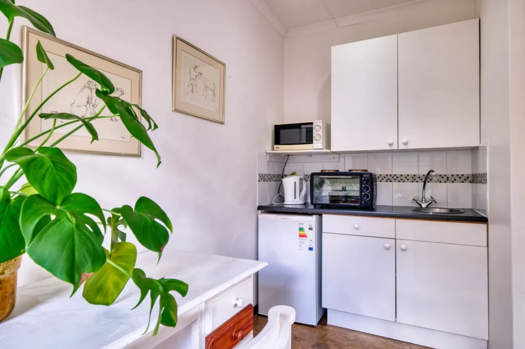 Kleine kitchenette met koelkastje, magnetron en spoelbak in een eenkamerwoning
