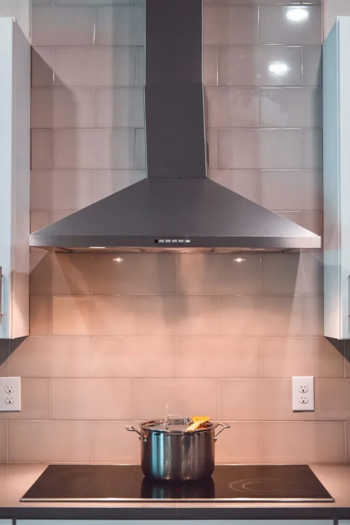 Kookpan op een inductiekookplaat onder een RVS-schouwkap in een lichte keuken