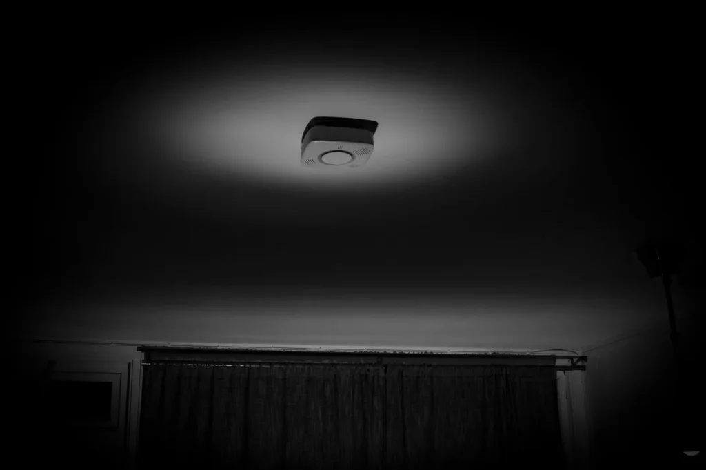 Rookmelder aan het plafond van een donkere slaapkamer: 's nachts is de rookmelder je wekker